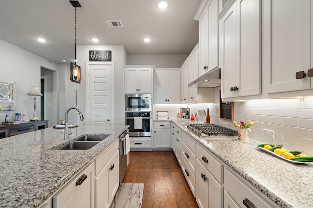 kitchen featuring light stone counters, dark wood-type flooring, white cabinetry, appliances with stainless steel finishes, and sink