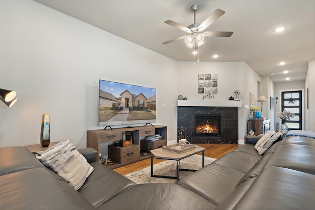 living room featuring wood-type flooring, a tiled fireplace, and ceiling fan