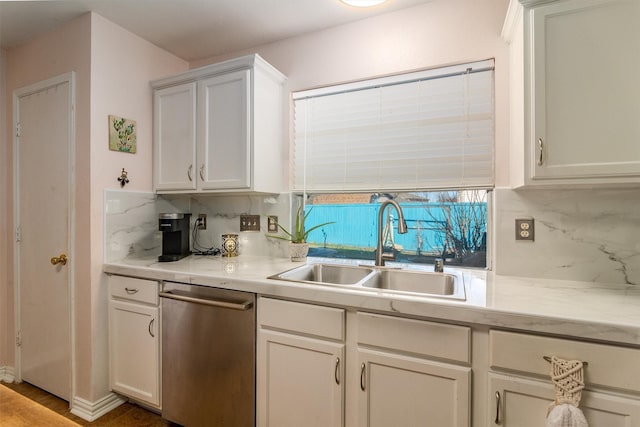 kitchen with stainless steel dishwasher, white cabinetry, backsplash, and sink