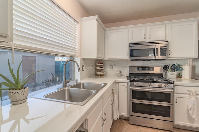 kitchen with sink, white cabinets, decorative backsplash, and appliances with stainless steel finishes