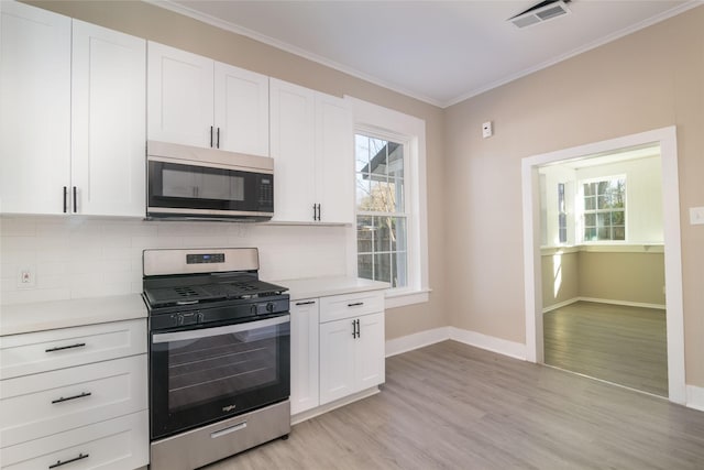 kitchen with white cabinetry, light hardwood / wood-style flooring, a healthy amount of sunlight, backsplash, and gas stove