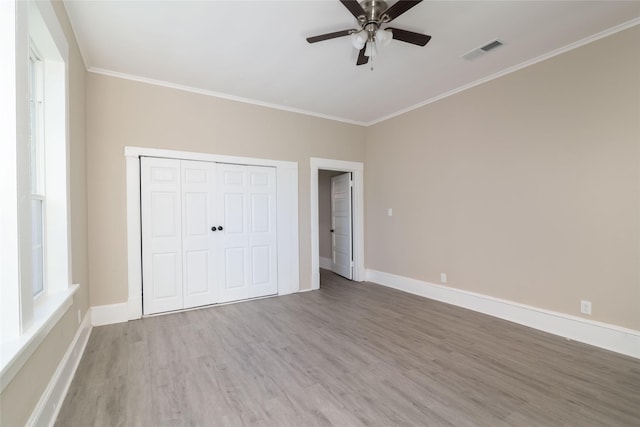 unfurnished bedroom with ceiling fan, crown molding, a closet, and hardwood / wood-style floors