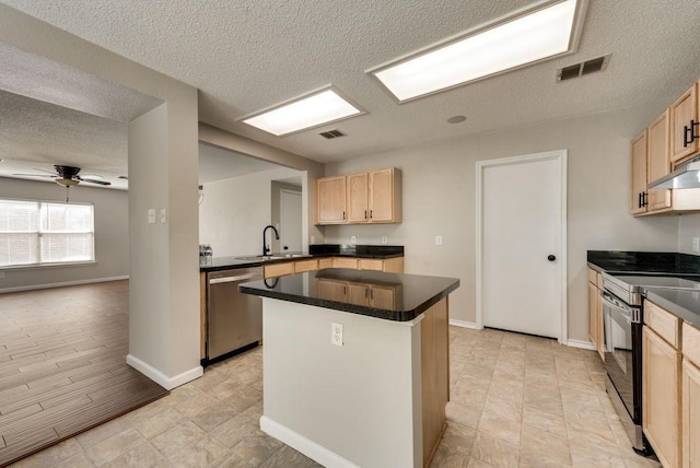 kitchen featuring sink, ceiling fan, light brown cabinetry, a kitchen island, and appliances with stainless steel finishes