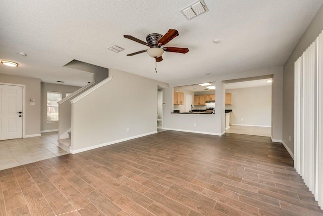 unfurnished living room with sink, a textured ceiling, and ceiling fan