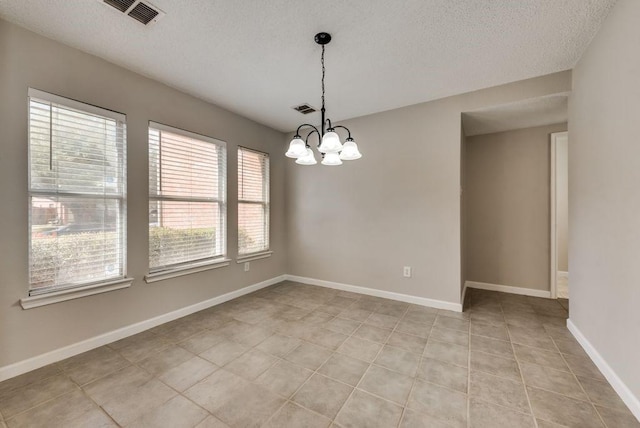 tiled empty room with an inviting chandelier and a textured ceiling