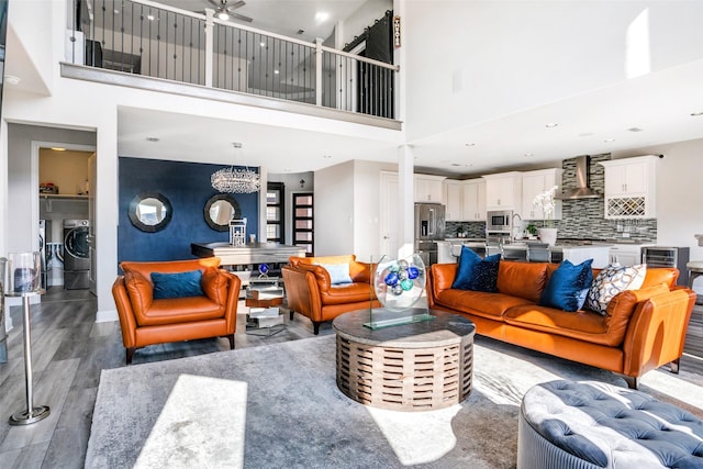 living room with wood finished floors, baseboards, a high ceiling, a notable chandelier, and washer and clothes dryer