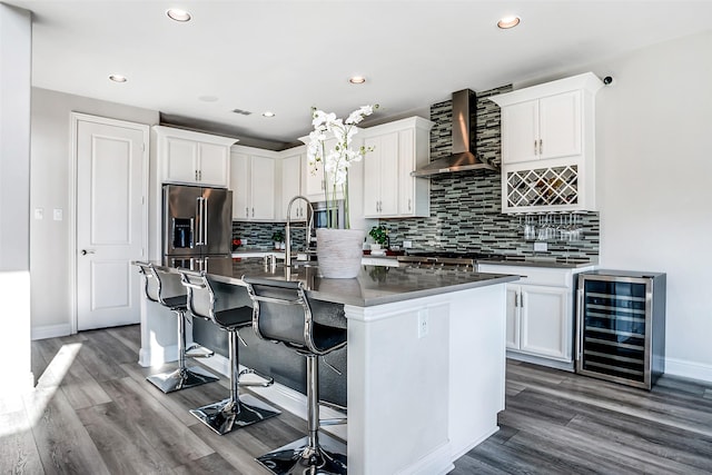 kitchen with beverage cooler, a kitchen breakfast bar, white cabinets, wall chimney exhaust hood, and dark wood-style flooring