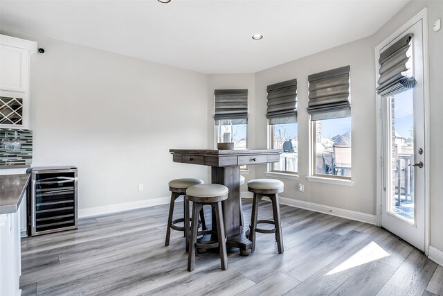 dining space with recessed lighting, baseboards, light wood-style floors, and beverage cooler