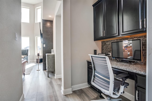 office area featuring baseboards, light wood-style flooring, and built in desk