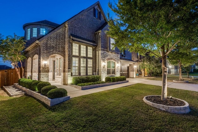 exterior space featuring fence, driveway, a front lawn, stone siding, and brick siding