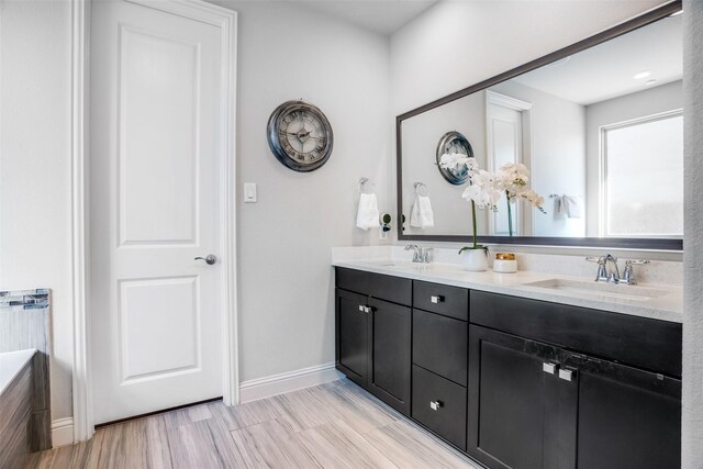 full bathroom with a sink, baseboards, and double vanity