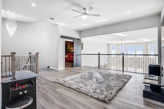 interior space featuring visible vents, a barn door, recessed lighting, ceiling fan with notable chandelier, and wood finished floors