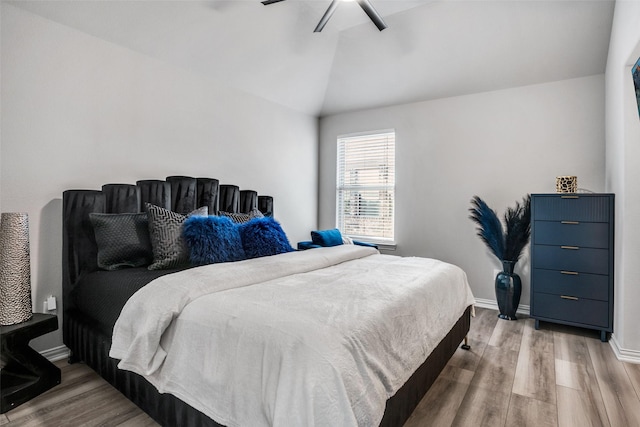 bedroom featuring baseboards, lofted ceiling, wood finished floors, and a ceiling fan