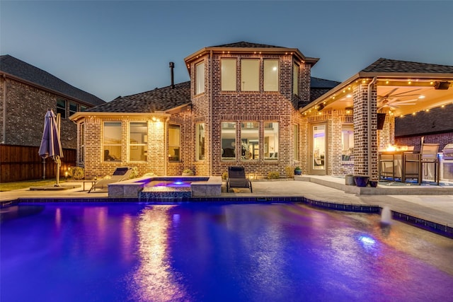 view of swimming pool with a patio area, a pool with connected hot tub, outdoor dry bar, and fence