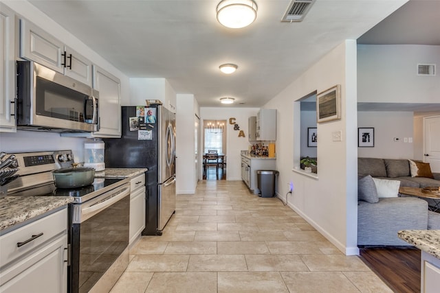 kitchen with stainless steel appliances, light stone counters, gray cabinets, and light tile patterned floors