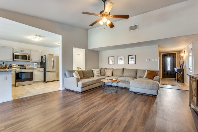 living room featuring lofted ceiling, ceiling fan, and light hardwood / wood-style flooring