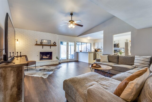 living room with ceiling fan, dark hardwood / wood-style flooring, a brick fireplace, and lofted ceiling