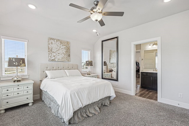 carpeted bedroom with lofted ceiling, ensuite bathroom, sink, and ceiling fan