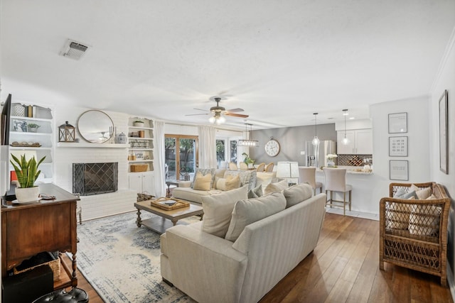 living room featuring a fireplace, dark wood-type flooring, and ceiling fan