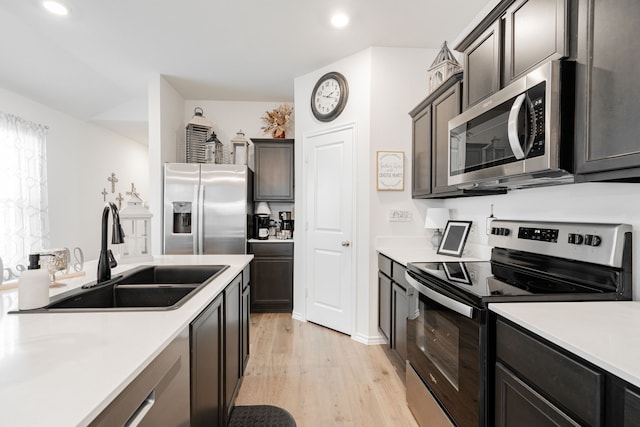 kitchen with stainless steel appliances, light hardwood / wood-style flooring, dark brown cabinets, and sink