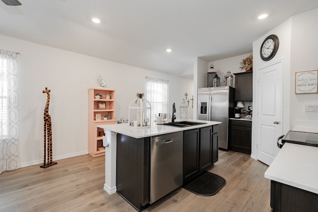 kitchen with sink, an island with sink, light wood-type flooring, and stainless steel appliances