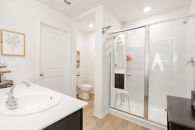 bathroom with toilet, wood-type flooring, vanity, and a shower with shower door