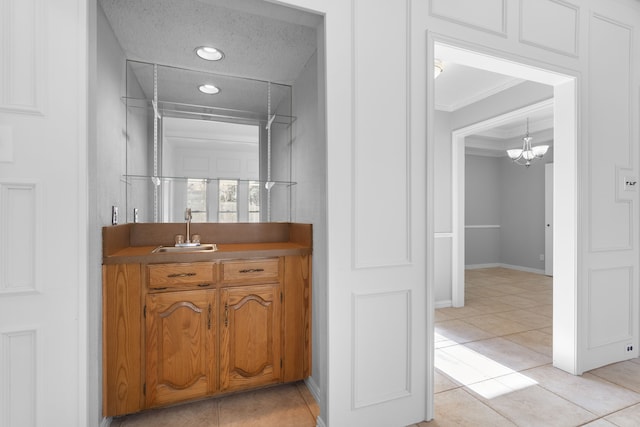 bathroom featuring vanity, tile patterned floors, a notable chandelier, and crown molding