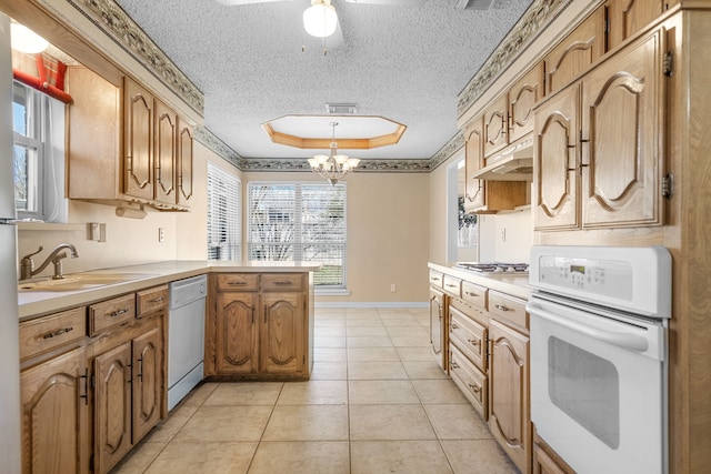 kitchen with white appliances, kitchen peninsula, a textured ceiling, a tray ceiling, and sink