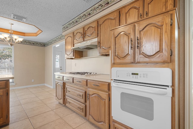 kitchen with an inviting chandelier, a textured ceiling, light tile patterned floors, white oven, and hanging light fixtures