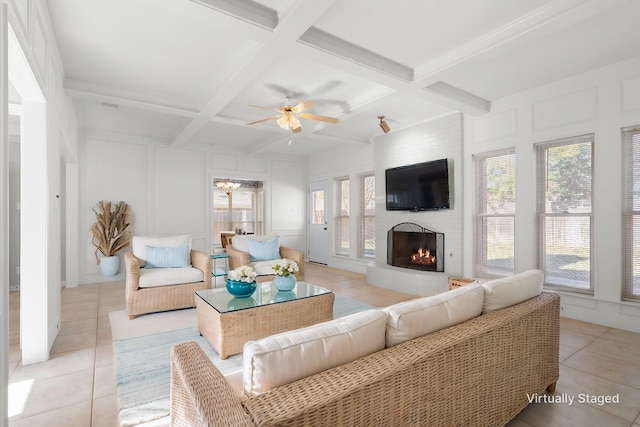 living room with beamed ceiling, ceiling fan, light tile patterned floors, and a large fireplace