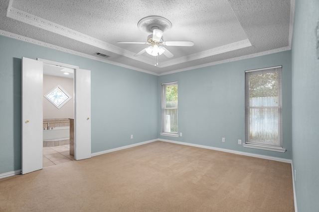 carpeted spare room with ornamental molding, ceiling fan, a raised ceiling, and a textured ceiling