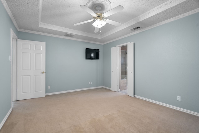 unfurnished bedroom featuring ornamental molding, ceiling fan, a tray ceiling, and light carpet