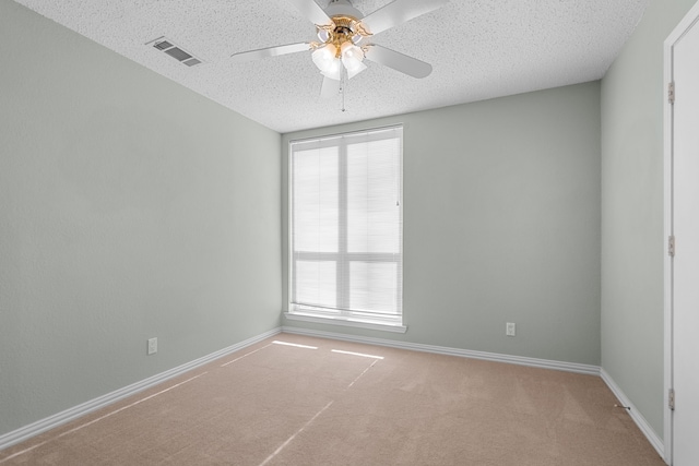 unfurnished room featuring ceiling fan, light colored carpet, and a textured ceiling