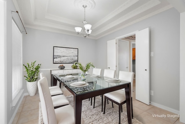 dining room with light tile patterned floors, ornamental molding, a tray ceiling, and a notable chandelier