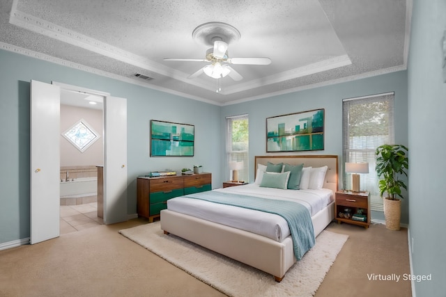 bedroom featuring ensuite bath, a textured ceiling, a raised ceiling, ceiling fan, and ornamental molding