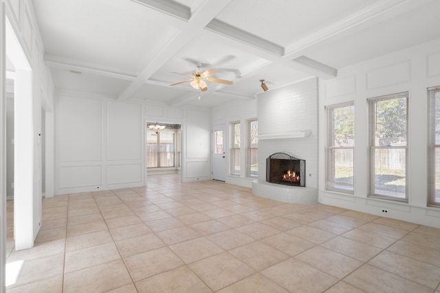 unfurnished living room with a brick fireplace, light tile patterned flooring, ceiling fan, and beamed ceiling