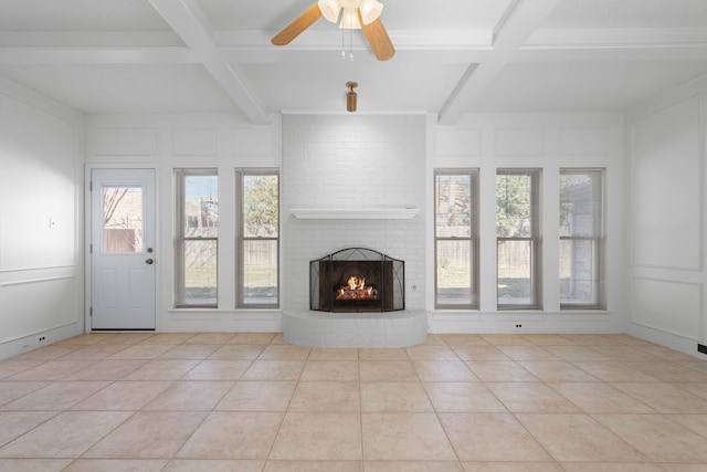 unfurnished living room with a fireplace, ceiling fan, light tile patterned floors, and beamed ceiling