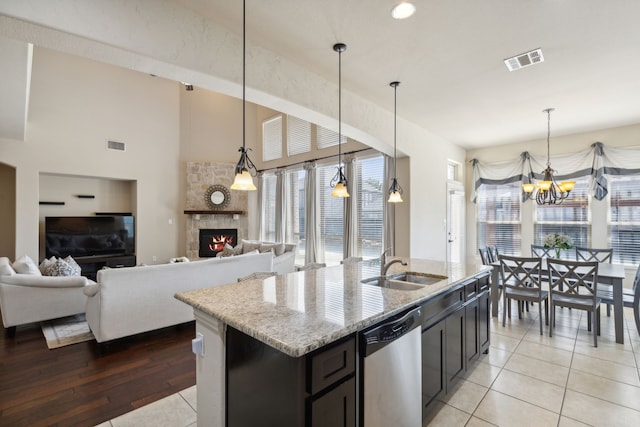 kitchen with light stone countertops, stainless steel dishwasher, pendant lighting, and a stone fireplace