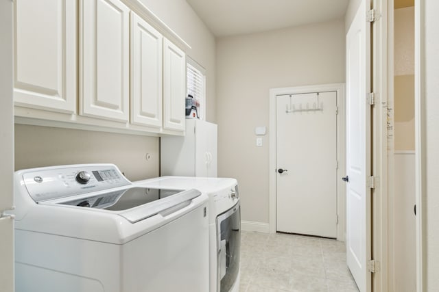 clothes washing area featuring cabinets and washer and clothes dryer