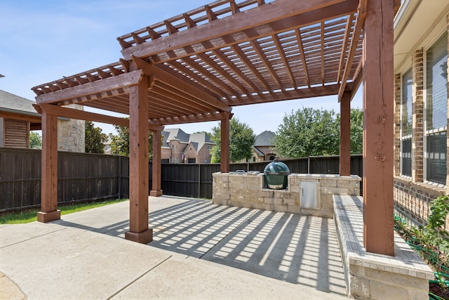 view of patio with exterior kitchen, area for grilling, and a pergola