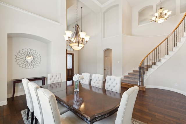 dining room featuring a towering ceiling, an inviting chandelier, and dark hardwood / wood-style flooring