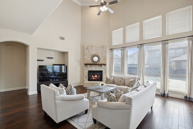 living room with a high ceiling, dark wood-type flooring, and a stone fireplace