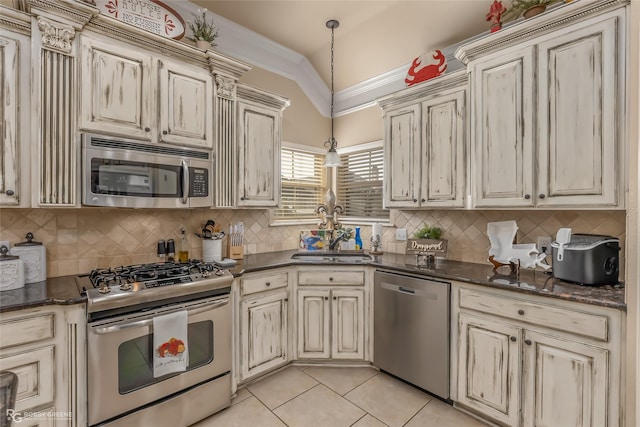 kitchen with lofted ceiling, appliances with stainless steel finishes, cream cabinetry, and sink