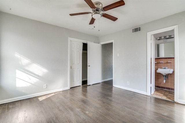 unfurnished bedroom with ceiling fan, dark hardwood / wood-style flooring, ensuite bathroom, and a closet