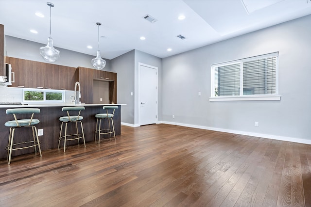 kitchen featuring dark wood-type flooring, pendant lighting, and a breakfast bar area