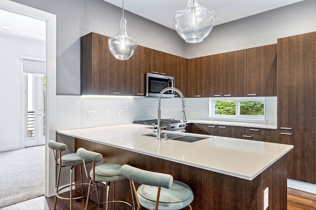 kitchen featuring light hardwood / wood-style floors, a breakfast bar, decorative backsplash, and hanging light fixtures