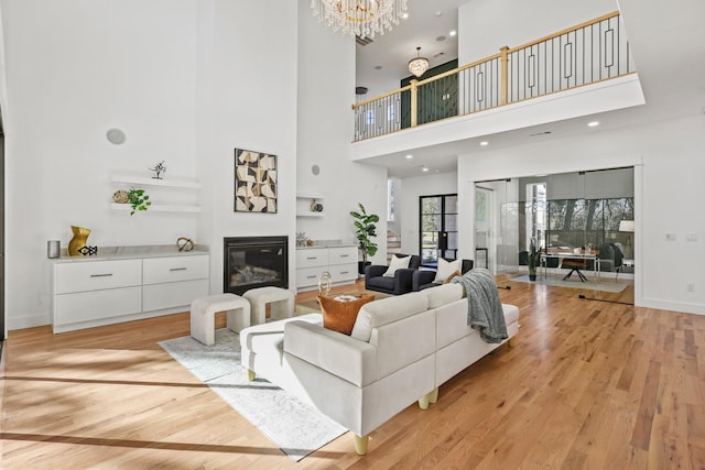 living room with a towering ceiling, light hardwood / wood-style floors, and a notable chandelier