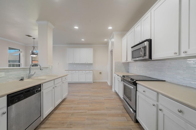 kitchen featuring decorative light fixtures, stainless steel appliances, crown molding, white cabinets, and sink