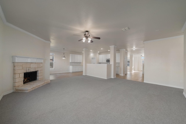 unfurnished living room featuring ornamental molding, light colored carpet, ceiling fan, and a fireplace