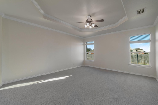 carpeted empty room featuring ceiling fan, ornamental molding, and a tray ceiling